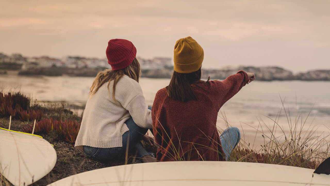 Kaksi nuorta naista istuu rantakivillä.