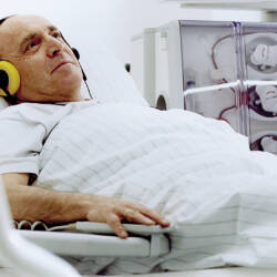 Mies makaa sängyssä kiinnitettynä hemodialyysilaitteeseen.