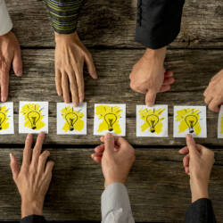 Ryhmä ihmisiä, joista näkyy vain käsi, osoittaa kortteja.