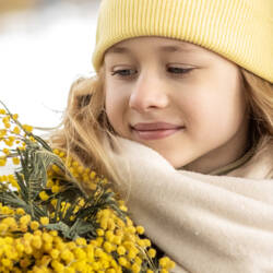 Nuorella tytöllä keltainen pipo päässä ja syksyisen keltaiset kukat käsissä.